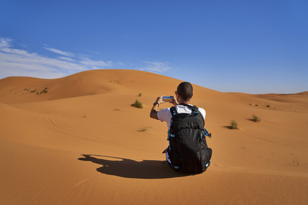 morocco-man-with-backpack-sitting-on-desert-dunemorocco-experts-travel